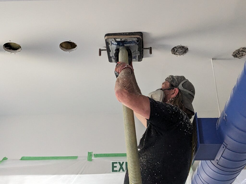 Dense-packed cellulose insulation machine and drilling holes for retrofitting walls without drywall removal.